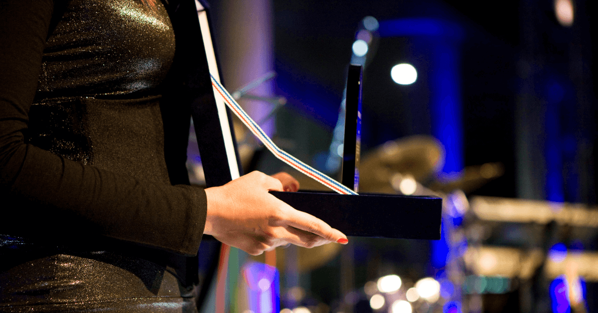 a person in a black dress holding a business award