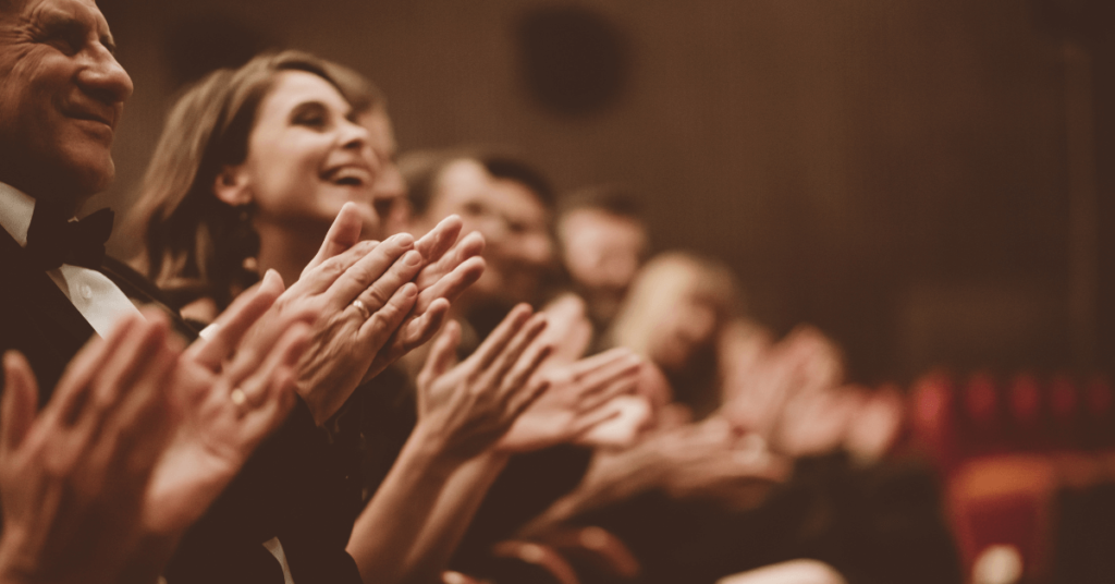 a group of people clapping in a theater