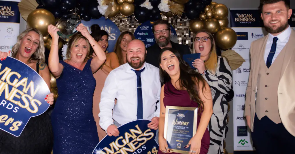 A Group of people at the Wigan Business Awards having their photo taken with an award.