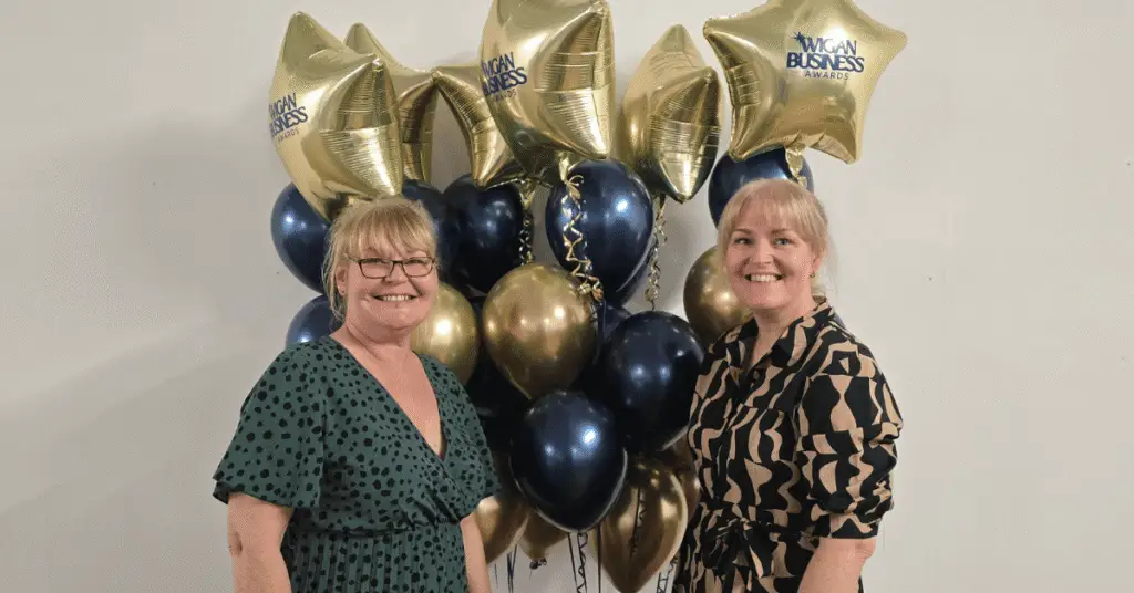 Image shows Wigan Business Awards Organisers, sisters Nichola Howard and Jo Leigh from Launch NW in front of a bunch of Gold Balloons