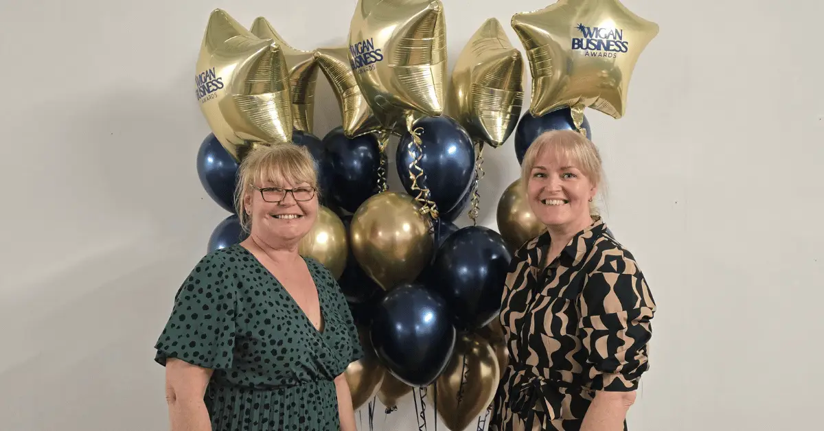 Image shows Wigan Business Awards Organisers, sisters Nichola Howard and Jo Leigh from Launch NW in front of a bunch of Gold Balloons