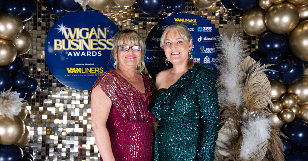 Wigan Business Awards organisers, Nichola Howard and Jo Leigh, stood in front of a decorative wall