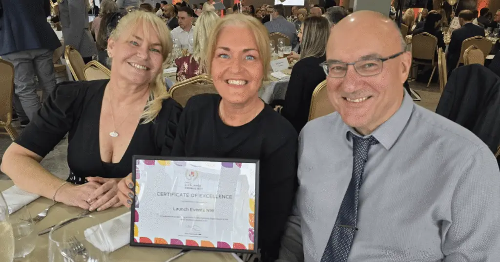 Nichola Howard, Jo Leigh and Phil Parramore from the Wigan Business Awards team smiling with their Greater Manchester Chamber Excellence Award for Marketing Impact