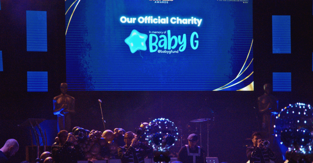 a large crowd of people in front of a large screen with the words baby g on it