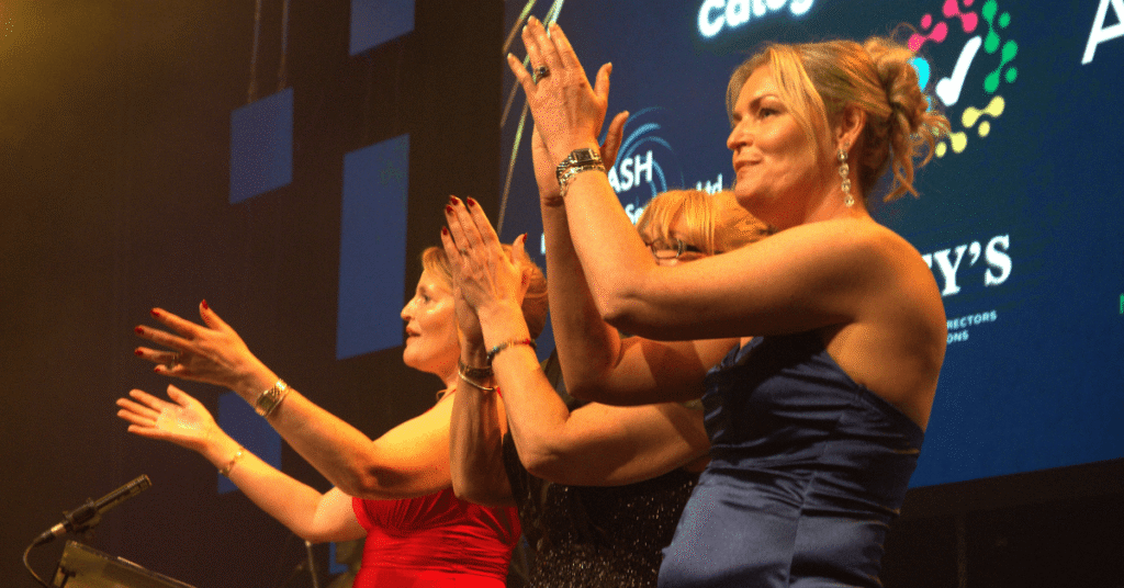 3 people clapping on the Wigan Business Awards atage