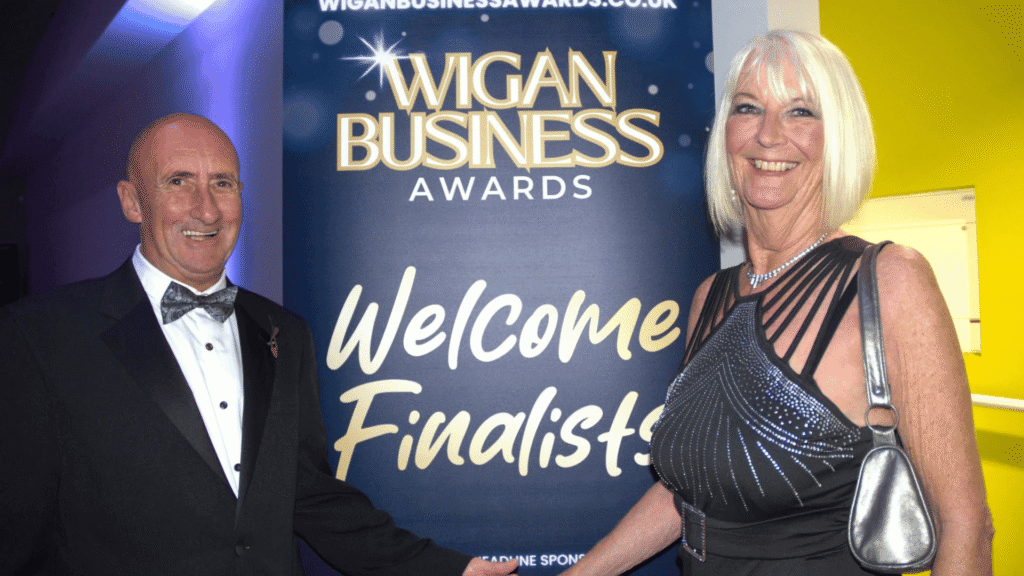 Wigan Business Awards Welcome finalists sign with a male and female smiling