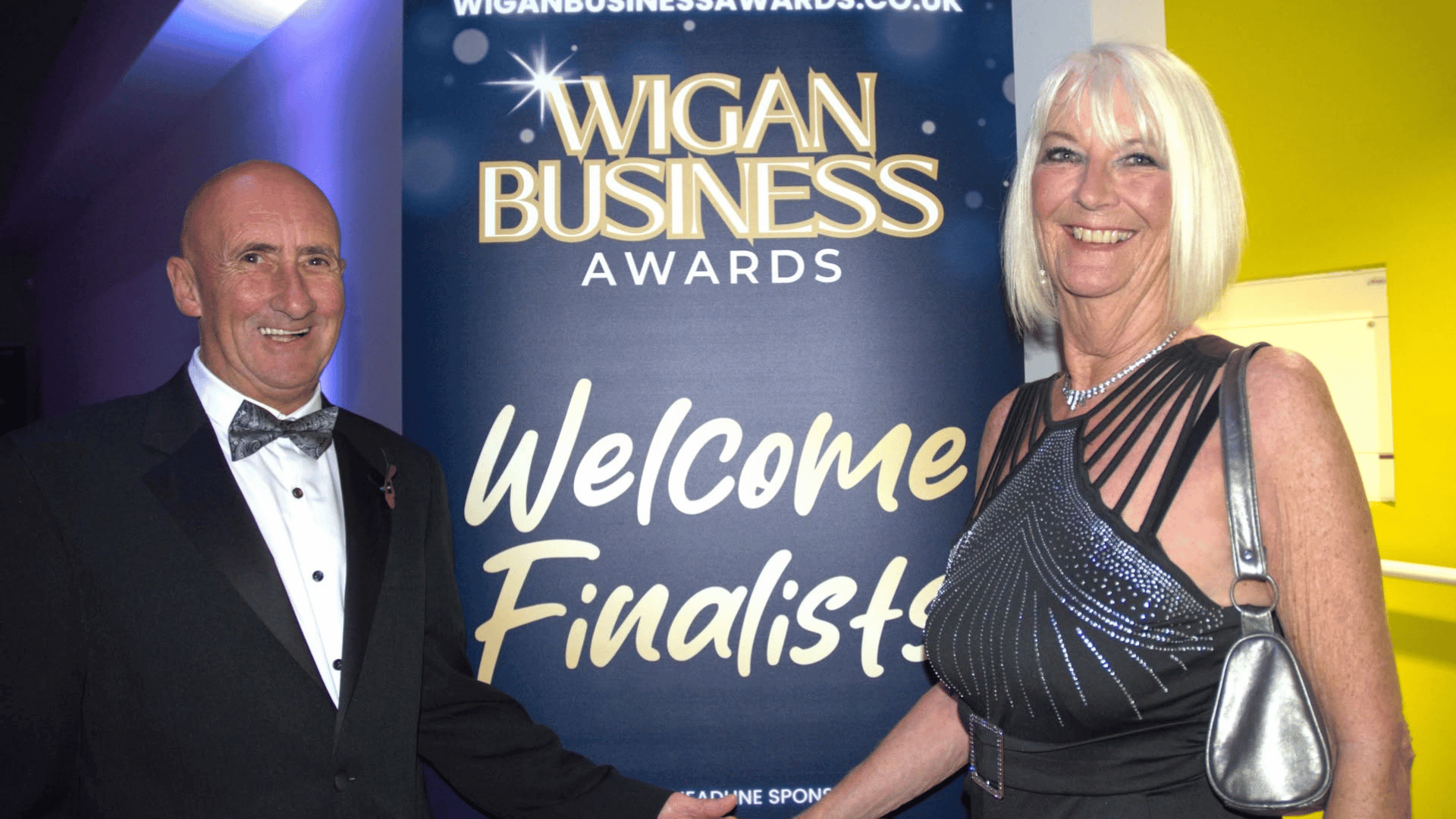 Wigan Business Awards Welcome finalists sign with a male and female smiling